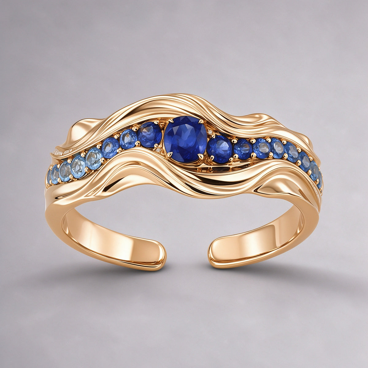 The Nereid Cuff in high-polish 18K warm gold vermeil sterling silver, a sculptural wave cuff set with gradient blue sapphires and a royal-blue centre stone, front view